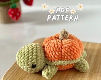 May include: A crocheted pumpkin turtle amigurumi toy with a green shell and an orange pumpkin shell. The toy is lying on a wooden surface. The text "PDF PATTERN" is written in white letters on a white background with white flowers.