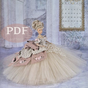 May include: A crochet doll wearing a pink and white dress with a tulle skirt. The doll has blonde hair and blue eyes. The doll is standing in front of a light blue background with a calendar that says "Miss November 1997".