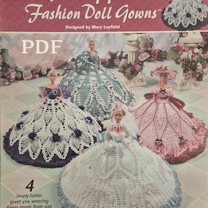 May include: A crochet pattern book titled "Pineapple Fashion Doll Gowns" featuring four doll gowns in white, pink, and blue. The cover includes the text "Annie's Attic" and "CROCHET". The dolls are wearing gowns made from size 10 crochet cotton thread and sport yarn.