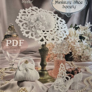May include: A white crocheted wedding slipper, hat, and purse. The hat is on a stand and the slipper is on a white surface with a string of pearls. The text "Annie's Miniature Shoe Society" is in the top right corner of the image.