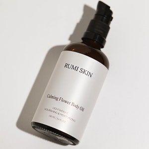 May include: A brown glass bottle with a black pump top. The bottle is labeled "RUMI SKIN Calming Flower Body Oil LIGHTWEIGHT NOURISHING & MOISTURIZING 100 ML | 3.4 FL.OZ."