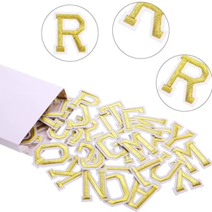 May include: A selection of gold embroidered letter patches, spilling from a white box. The letters are in a bold, serif font with a white border. Three circular insets show close-ups of the letter "R".