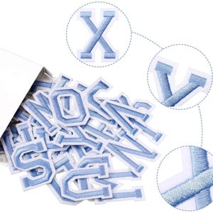 May include: A selection of light blue embroidered letter patches with white edging, emerging from a white box. The letters are in a classic serif font. Close-up details show the stitching and fabric texture.