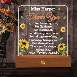 May include: A clear acrylic plaque with the text "Miss Harper Thank You" and a message of gratitude. The plaque features sunflower and leaf graphics and sits on a wooden base with a small light.
