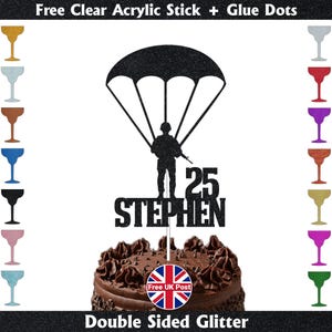 May include: A black glitter cake topper with a soldier under a parachute, the number 25, and the name "Stephen". The topper is on a chocolate cake. Text at the top reads "Free Clear Acrylic Stick + Glue Dots". Includes a "Free UK Post" logo.