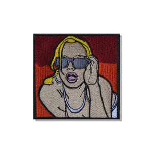 Puede incluir: Un parche bordado cuadrado con una ilustración estilizada de una persona de cabello rubio que usa gafas de sol oscuras y un collar. La figura tiene la boca abierta y se encuentra sobre un fondo de tonos rojo oscuro y naranja intenso.