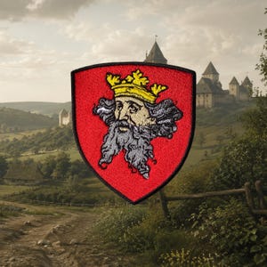May include: A shield-shaped embroidered patch featuring a red background with a black border. The central design depicts a bearded figure with a grey beard and hair, wearing a yellow crown, rendered in a detailed, stitched embroidery style.