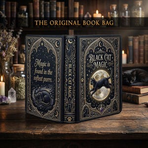 May include: A black book bag with gold accents and the text "THE ORIGINAL BOOK BAG". The bag features a design with a black cat, moon, and stars, with the words "Black Cat Magic" and "Magic is found in the softest purrs."