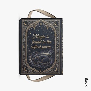 May include: A black book-style bag with a cream-colored handle. The cover features a sleeping black cat illustration with the text "Magic is found in the softest purrs." Ornate gold-colored embellishments frame the text and cat.