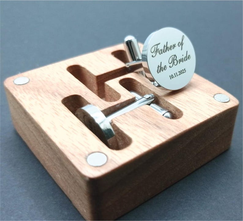 Round silver cufflinks engraved with the words “Father of the Bride” and the date “10.11.2025,” displayed on a wooden presentation box.