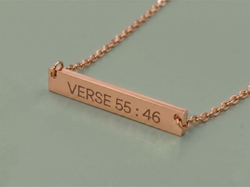 A Rose Gold necklace with a rectangular pendant. The pendant is engraved with the words "Verse 55:46" in a bold font. The necklace chain is delicate and has a beaded design.