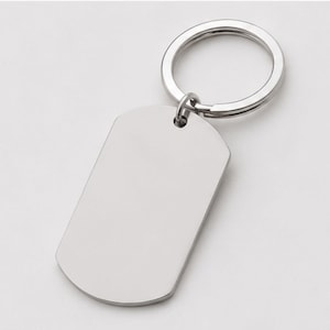 Close-up product photo of a blank silver stainless steel keychain with a polished finish. The dog-tag-style pendant is attached to a matching silver key ring and displayed on a clean light-gray background, emphasizing the customizable engraving surface for personalized handwriting, fingerprint, memorial messages, names, dates, logos, or custom text.