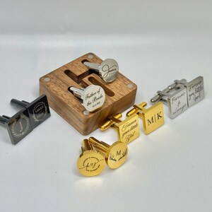 Puede incluir: Una variedad de gemelos personalizados en tonos plateados y dorados, algunos con texto e iniciales grabadas. Un juego se muestra en una caja de madera. Los gemelos presentan varios dise&ntilde;os, incluyendo iniciales, nombres y frases.