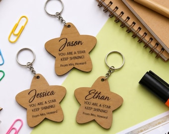 May include: Three star-shaped wooden keychains with metal rings. Each keychain is engraved with a name, Jason, Jessica, or Ethan, followed by the text YOU ARE A STAR KEEP SHINING! From Mrs. Howard in a combination of script and block fonts.