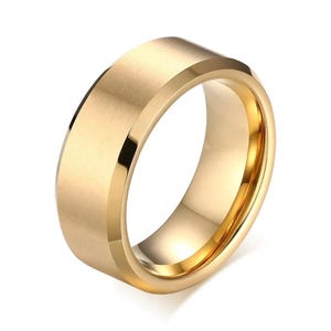 A gold-colored ring with a flat top and beveled edges. The ring has a polished interior and a matte finish on the exterior, reflecting light. This piece of jewelry is suitable for everyday wear.