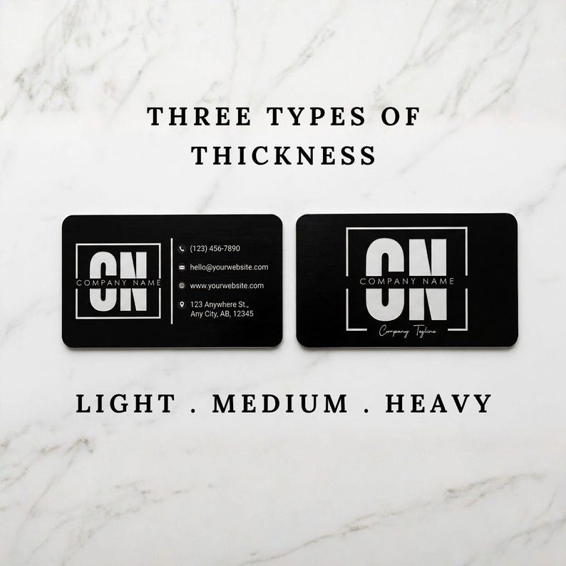 Comparison of metal business card thickness options labeled light, medium, and heavy on a marble background