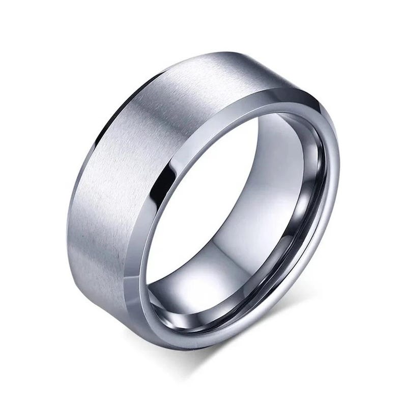A silver-colored ring with a brushed, flat center band and polished beveled edges. The ring has a modern, minimalist design. The ring is a jewelry item.