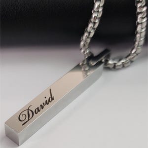 Close-up of engraved Silver bar pendant showing personalized name detail and smooth polished finish.