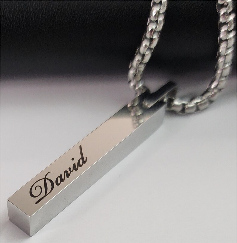 Close-up of engraved Silver bar pendant showing personalized name detail and smooth polished finish.