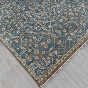May include: A blue and beige patterned rug with a geometric design. The rug has a distressed look, with a faded appearance. The edges are finished with a fringe.