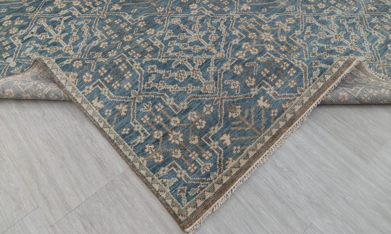 May include: A blue and beige patterned rug with a geometric design. The rug has a distressed look, with a faded appearance. The edges are finished with a fringe.