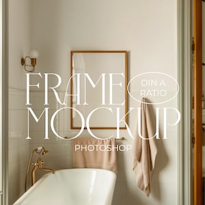 May include: A gold frame mockup in a bathroom setting. The frame is hanging on a white tiled wall above a white bathtub. A towel hangs on a hook to the right of the frame. The text "FRAME MOCKUP" and "DIN A RATIO" is superimposed on the image.