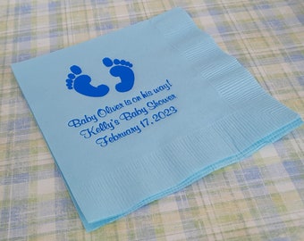 May include: Light blue paper napkin with blue baby footprints and the text "Baby Oliver is on his way! Kelly's Baby Shower February 17, 2023".