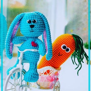 May include: A handmade crochet bunny riding a white bicycle, pulling a carrot in a basket. The bunny is blue with pink inner ears and a red heart. The carrot is orange with green yarn for the top.