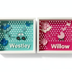 Może przedstawiać: Dwa oprawione dzieła sztuki z imionami dzieci. Jeden ma turkusowe tło z samochodem, balonami, motylami, bucikami i imieniem "Westley". Drugi ma różowe tło z wózkiem, balonami, motylami, bucikami i imieniem "Willow".