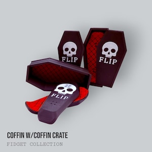 Könnte beinhalten: Schwarze, Sarg-förmige Fidget-Spielzeuge mit einem weißen Totenkopf und dem Wort "FLIP" aufgedruckt. Die Särge haben rote Innenräume. Das Bild enthält auch den Text "COFFIN W/COFFIN CRATE" und "FIDGET COLLECTION".