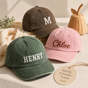 May include: Three baseball caps in dark brown, sage green, and light pink. The brown cap features a white letter M, the green cap has the name HENRY in white, and the pink cap has the name Chloe in brown. A tag reads: best fit: 6 months - 3 years.