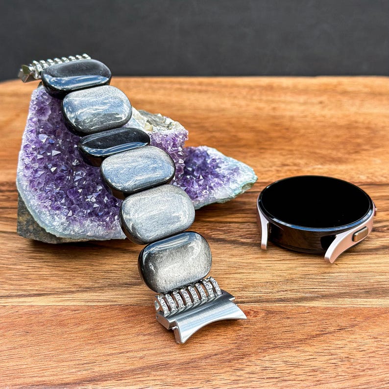 A handmade Silver Obsidian Gemstone watch band laid flat, with the connector and beads arranged neatly to show off the luxurious details.