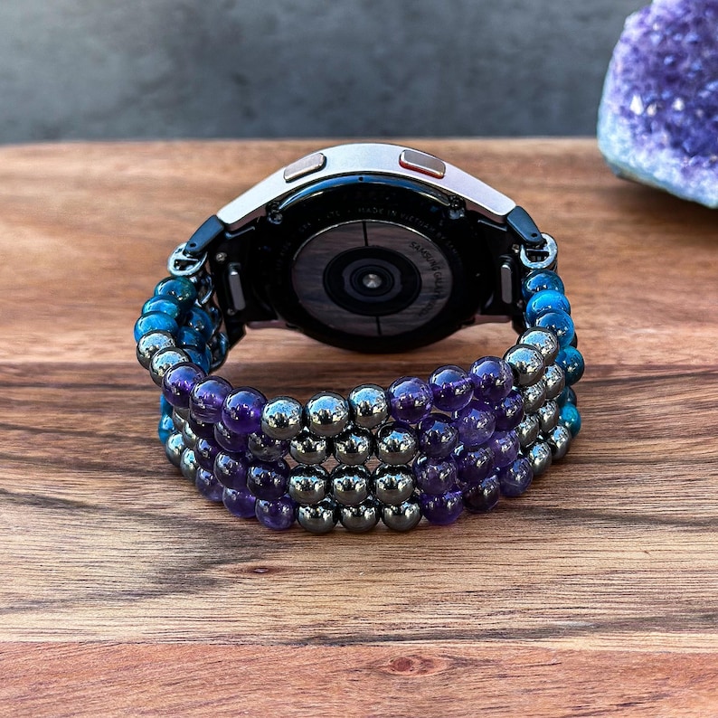 Enhance your Samsung Galaxy Watch with a handcrafted band adorned with Black Hematite, Purple Amethyst, and Blue Tiger Eye gemstones. This stylish accessory is perfect for those who appreciate beauty and craftsmanship.
