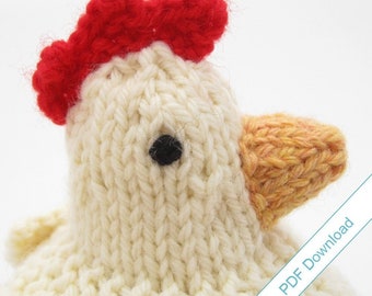 May include: A knitted white chicken with a red comb and a yellow beak. The chicken has a black eye and is a handmade toy.