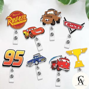 May include: A collection of cartoon character badge reels featuring designs from the movie Cars. The reels include Lightning McQueen, Mater, and the Rust-eze logo, along with other Cars-themed graphics. Each reel has a white retractable cord.