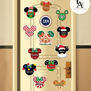 May include: A collection of Christmas-themed Mickey Mouse head-shaped ornaments with names like Vincent, Brandon, and Catherine. The ornaments feature festive designs, including candy canes, bows, and Santa hats, and are displayed on a door.