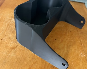 May include: A black plastic cup holder with two cup slots. The holder has a curved base and a flat top.