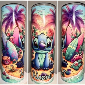 Op de afbeelding: Roestvrijstalen beker met een kleurrijke illustratie van een blauw stripfiguur, surfplanken en een tropisch strandlandschap. De naam "Naomi" staat onderaan de beker.