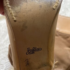 May include: Close-up of the back of a pair of tan leather boots with a stitched seam and the text "Joolia's USA" and "9 1/2" written on the back of the boot.