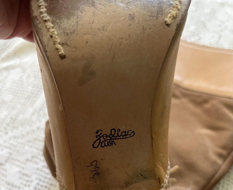 May include: Close-up of the back of a pair of tan leather boots with a stitched seam and the text "Joolia's USA" and "9 1/2" written on the back of the boot.