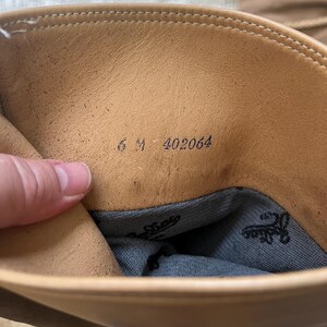 May include: The inside of a tan leather boot with the size 6 M and number 402064 printed on the insole.