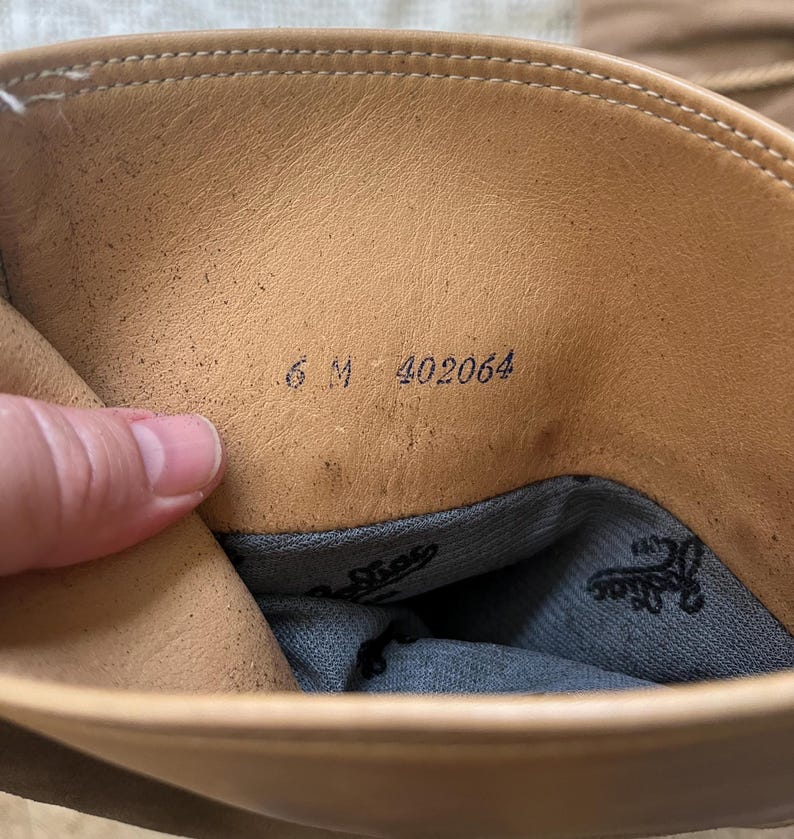 May include: The inside of a tan leather boot with the size 6 M and number 402064 printed on the insole.