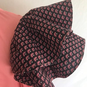 May include: A pink and black patterned fabric with a ruffled edge. The fabric is folded over itself, creating a layered effect.