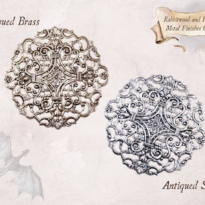Pu&ograve; includere: Immagine che mostra due finiture metalliche decorative: Ottone Antico e Argento Antico. La finitura in ottone ha un aspetto caldo e invecchiato, mentre la finitura in argento offre un aspetto brillante e lucido. Il design presenta intricati motivi a spirale. Il testo "Rabbitwood and Reason Metal Finishes Chart" &egrave; visibile.