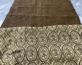 Op de afbeelding: Een bruine tafelrunner met een beige en groen bloemenpatroon. De runner is gemaakt van een textuurrijke, geweven stof.