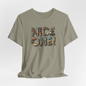 May include: A heather grey t-shirt with the words "NICE ONE!" printed on the front. The letters are made up of a collage of images.