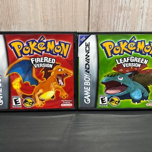 May include: Two Game Boy Advance video game cartridges, one red and one green. The red cartridge has the text "Pokémon FireRed Version" and features a red and orange Pokémon. The green cartridge has the text "Pokémon LeafGreen Version" and features a blue and green Pokémon.