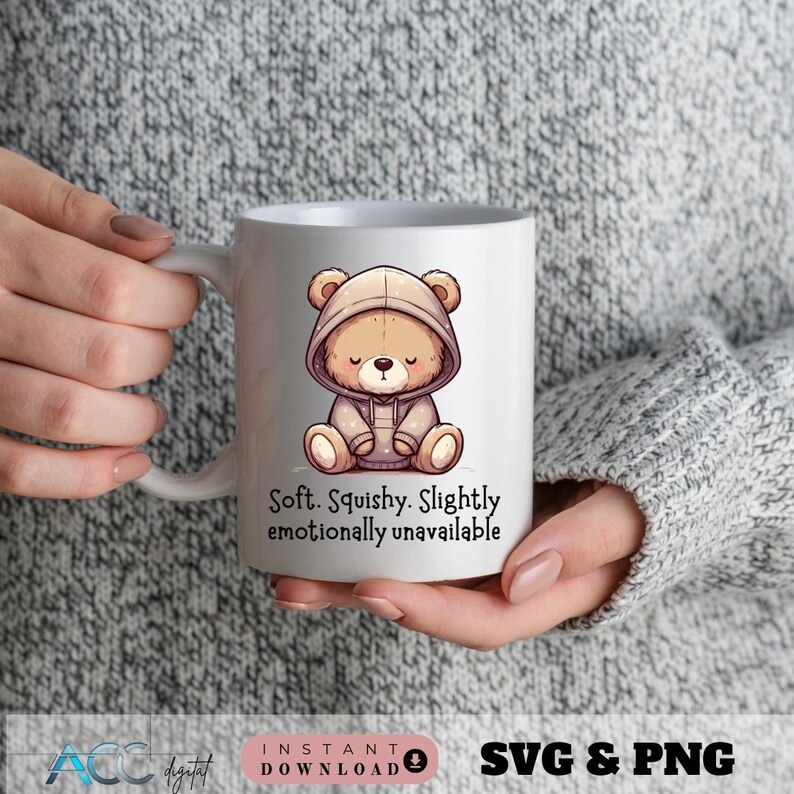 May include: White ceramic mug featuring a cartoon bear in a hoodie. The bear is light brown with a closed-eye expression. Text on the mug reads: "Soft. Squishy. Slightly emotionally unavailable."