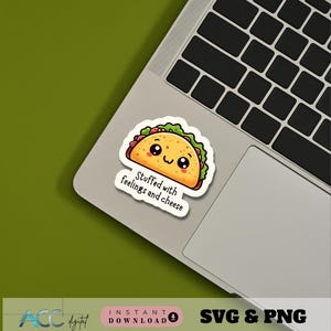 May include: A colorful taco sticker with a smiling face and the text "Stuffed with feelings and cheese." The sticker is on a laptop, with a green background. The taco has a light brown shell, green lettuce, and red tomatoes.