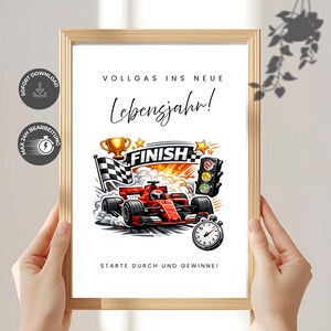 Puede incluir: Una impresión enmarcada con temática de carreras. La obra de arte presenta un coche de carreras rojo, una bandera a cuadros, un trofeo y la palabra "FINISH". El texto incluye "VOLLGAS INS NEUE Lebensjahr!" y "STARTE DURCH UND GEWINNE!"